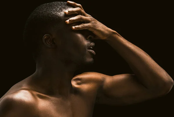 Africano facepalm. Sexy hombre africano se cubrió la cara con su mano, vista de perfil de un joven afroamericano desnudo posando sobre fondo negro tocando su cara con su mano,. Imagen tonificada —  Fotos de Stock