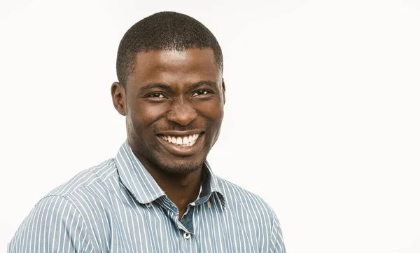 Handsome African guy with white-toothed smile looking at camera, dark-skinned well-dressed young man cut out on white background. Concept of dental care. Copy space at right. Toned image — Stock Photo, Image