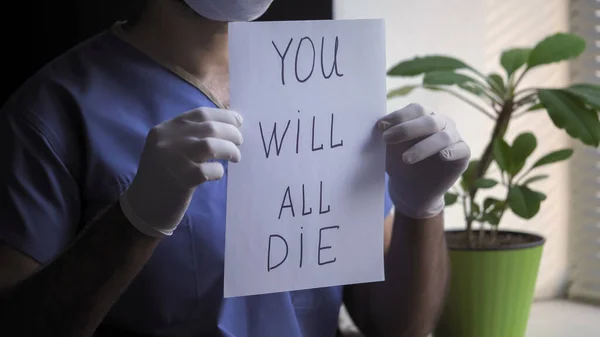 El doctor muestra una mala predicción sobre la muerte sosteniendo papel en blanco con una inscripción que dice que todos morirán. Pronóstico desfavorable de la enfermedad, concepto de brote de virus —  Fotos de Stock