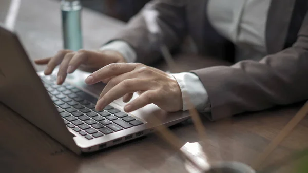 Κοντινό πλάνο των businesswomans χέρια δακτυλογράφηση στο πληκτρολόγιο του laptop, γυναίκα στην επιχείρηση formalwear λειτουργεί με υπολογιστή που κάθεται στο γραφείο με απολυμαντικό σε αυτό — Φωτογραφία Αρχείου