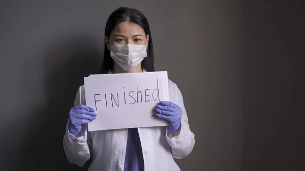 Dokter kecantikan wanita memegang kertas dengan tulisan FINISHED. Dokter yang gembira melaporkan akhir dari epidemi oleh coronavirus — Stok Foto