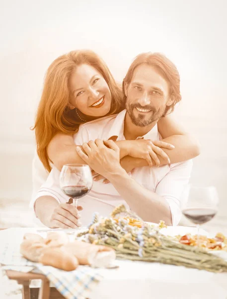 Schönes Paar, das sich im Freien ausruht, glückliche Frau, die ihren Mann umarmt. Mann und Frau essen und trinken Wein an der frischen Luft vor dem Hintergrund des Meeres. Getöntes Bild — Stockfoto