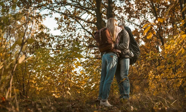 Bacio di backpackers innamorato abbracciare mentre in piedi da solo sullo sfondo della foresta autunnale all'aperto — Foto Stock