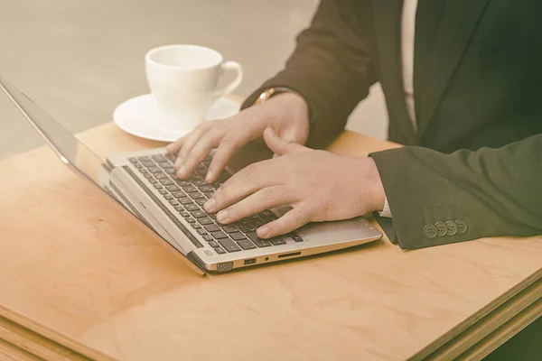 Επιχειρηματίας που χρησιμοποιεί φορητό υπολογιστή στο δρόμο καφέ σε εξωτερικούς χώρους. Κοντινό πλάνο των αρσενικών χεριών δακτυλογράφησης στο πληκτρολόγιο laptop. Δουλειά εν κινήσει. Τονισμένη εικόνα — Φωτογραφία Αρχείου