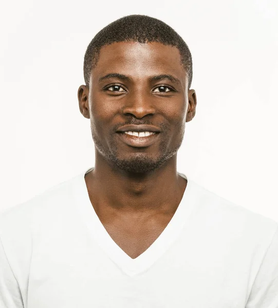 Pozitív afro-amerikai férfi, vigyorog a kamerába. Sötét bőrű, vidám férfi fehér pólóban, fehér háttérrel. Előnézet — Stock Fotó
