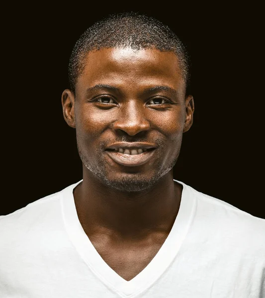Un Afro-Américain souriant regardant la caméra. Portrait d'homme à la peau foncée en t-shirt blanc découpé sur fond noir. Gros plan — Photo