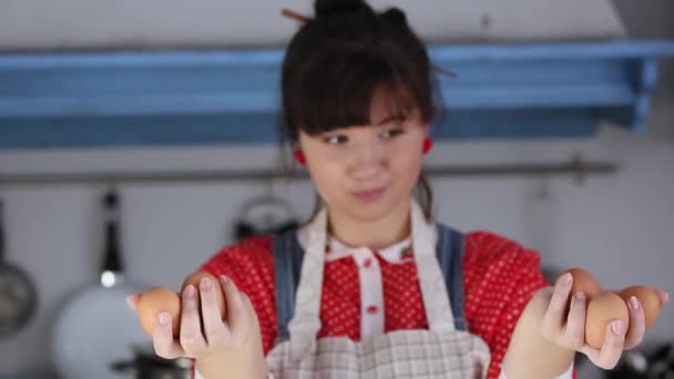 Puzzled cuoco e panettiere ragazza con le uova di pollo in mano guardando la fotocamera con attenzione ricordando la ricetta per il test. ragazza cucina in una cucina d'epoca. Prore 422 — Video Stock