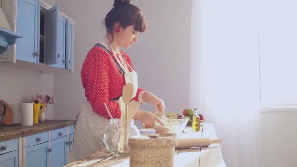 X8 aceleró las imágenes de una joven cocinando en la cocina azul. Hermosa chica amasa ingredientes de masa contra una ventana soleada brillante. Prores 422 — Vídeo de stock