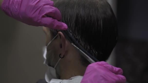 Γυναίκα κομμώτρια κόβει τον άνθρωπο σε μιας χρήσης ροζ γάντια, περίοδο του coronavirus άνθρωπος σε προστατευτική μάσκα κάθεται στην καρέκλα. Αυτοαπομόνωση έννοια. Κομμωτήριο. Πρότυπα 422 — Αρχείο Βίντεο