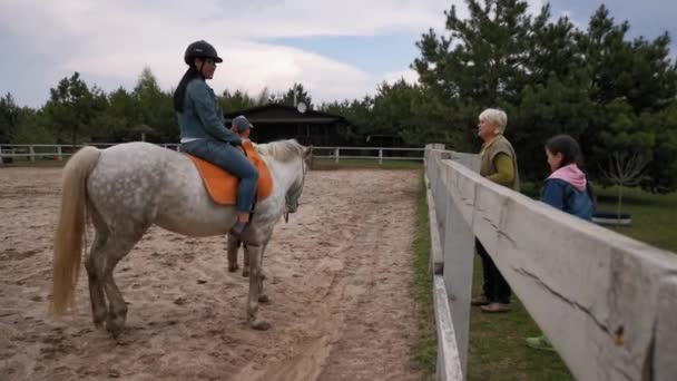 乗馬用具の女性は馬の背部に坐る。アジア人は乗ることを学ぶ。牧場のコンセプト。422番です。2020年5月。ウクライナのキエフ — ストック動画