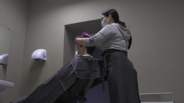 一番下のビュー美容師は、隔離コロナウイルスの期間中に保護マスクのオードで自宅で男をカットします。美容師のコンセプト。第四百二十二条 — ストック動画
