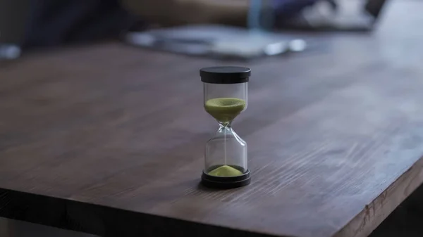 Hourglass on doctors table in medical office. Focus on hourglass with pouring sand. Transience of time concept — Stock Photo, Image