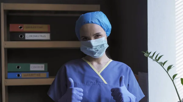 Jempol ke atas tanda dari seorang dokter lelah. Pekerja medis wanita menunjukkan sikap mendorong yang berarti bahwa semuanya akan baik-baik saja. Konsep Pandemic 2020 — Stok Foto