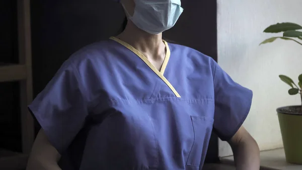 Lægens torso i blå beskyttende uniform stående ved vinduet. Kvindelig medicinsk arbejder i arbejde under coronavirus eller covid-19 virus pandemi. Medicin og sundhedspleje koncept - Stock-foto