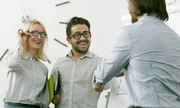 Affärspartners skakar hand. Kollegor hälsar varandra skakande händer, fokusera på en leende man och kvinna i glasögon som står mot en ljus kontorsvägg. Tonad bild — Stockfoto