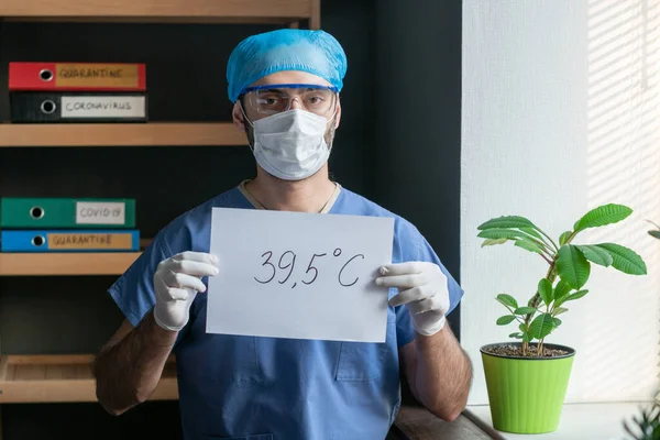 Dokter memegang formulir kertas dengan tulisan 39.5C. Medis laki-laki dalam seragam pelindung memperingatkan peningkatan suhu yang berbahaya menjadi 39,5 derajat Celcius yang merupakan gejala penyakit virus — Stok Foto