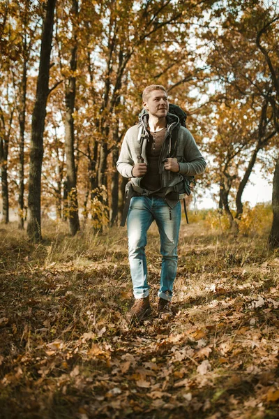 Stedelijke bewoner in het wild. Backpacker wandelen in de herfst bos. Kaukasische jonge man toerist met een grote rugzak wandelingen in het najaar bos — Stockfoto
