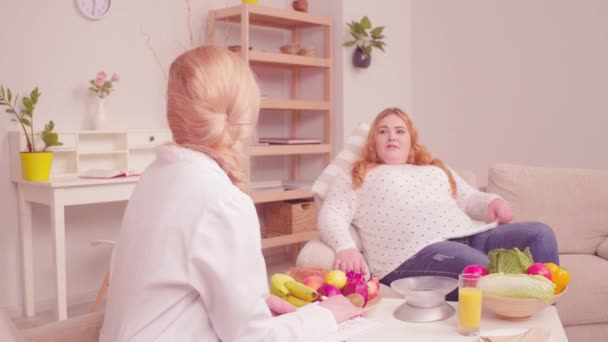 Overweight client consulted by a nutritionist. Young girl with overweight problem came to the doctor to have health tests. Proper nutrition concept. Tone video. Prores 422 — Stock Video