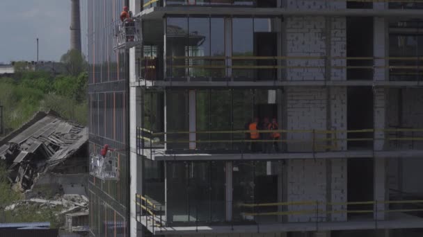 Zooma ut kameran för att bygga ett nytt bostadshus under uppförande eller ett kontorshotell med byggare som klättrar i externa hissar. Kiev, Ukraina. Maj 2020. Prores 422 — Stockvideo