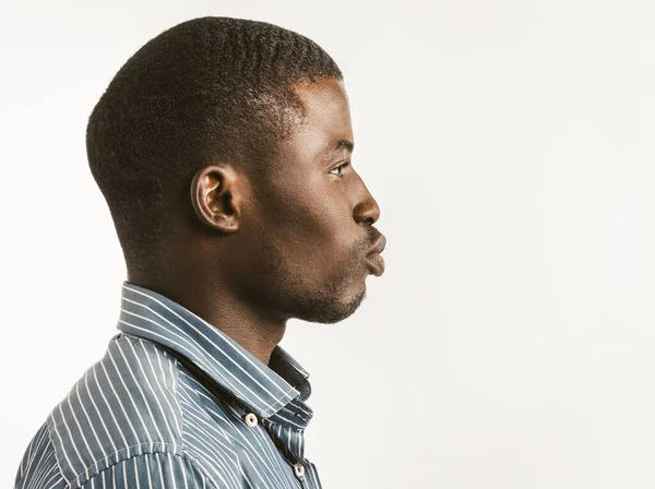 O homem de negócios preto afro-americano em uma camisa olha para o lado com lábios estendidos quanto a um beijo. Corte em fundo branco com espaço de cópia no lado direito. Imagem tonificada — Fotografia de Stock