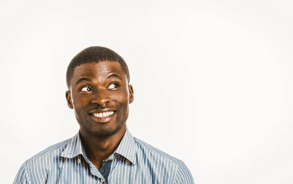 Den leende afrikanske amerikanske mannen tittar upp lekfullt åt sidan. Ung affärsman med kopieringsutrymme på höger sida. Friska tänder koncept. Tandvård koncept. Känslor koncept. Tonad bild — Stockfoto
