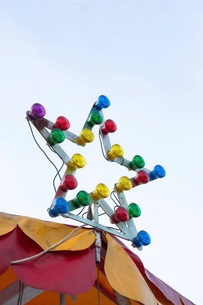 Lamp met veelkleurige gloeilampen. Stervormige verlichting aan de bovenkant van de draaimolen. Verlichtingsconcept — Stockfoto