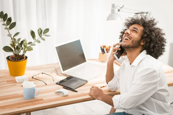 Kreatív fiatalember beszél mobilon. Arabik diák mosolyog beszélgetni okostelefonon, miközben dolgozik otthonról. Szabadúszó ötlet. Tonozott kép — Stock Fotó