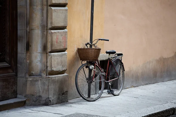 Bicicleta de pé perto da parede do edifício antigo. Bicicleta feminina com cesta de vime na frente é presa com corrente para postar na rua da cidade europeia. Papel de parede ou fundo. Copiar espaço no lado direito — Fotografia de Stock