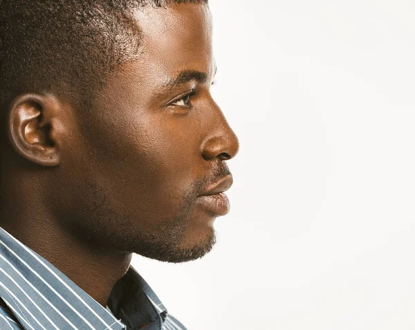 El hombre afroamericano serio parece confiado. Perfil cercano del atractivo chico de piel oscura aislado sobre fondo blanco. Copia espacio en el lado derecho. Imagen tonificada —  Fotos de Stock