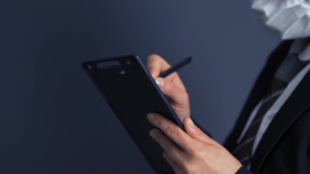 Business woman in a protective mask in a black business suit makes notes in documents holding a tablet in hands. Business concept. Close-up on hands. Prores 422 — Stock Video