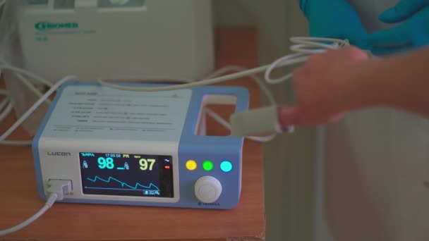 Patientens hand med anslutet pulsoximeter sensorelement. Medicinsk diagnosutrustning. Stadssjukhuset. Maj 2020, Brovary, Ukraina — Stockvideo