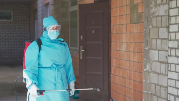 보호용 양복을 입은 여자는 건물 의외 벽을 소독 한다. 전염병 이 창궐하는 동안 병원 건물의 감염. 시립 병원. 2020 년 5 월, 우크라이나 브로바리 — 비디오