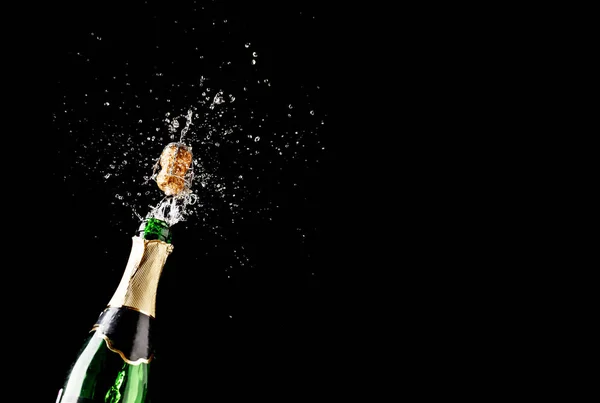 Cortiça voa para fora da garrafa de champanhe isolado em fundo preto — Fotografia de Stock
