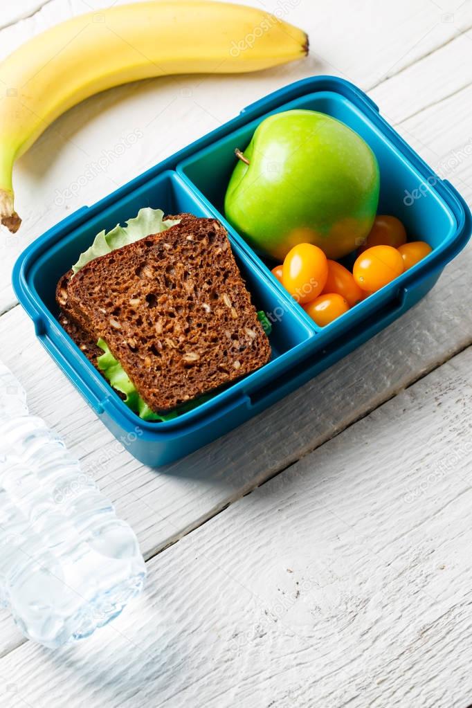 Image of useful snack from tomato, apple, sandwich in container
