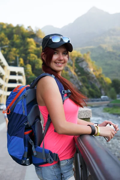 Image of brunette tourist with backpack backdrop of mountains — Stock Photo, Image