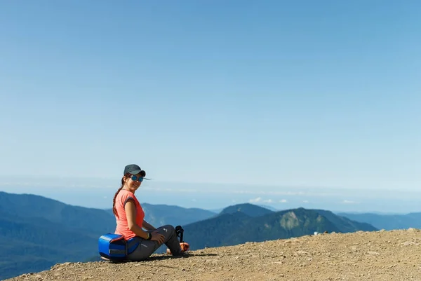Tepenin kenarında oturan güneş gözlüklü kız fotoğrafı — Stok fotoğraf