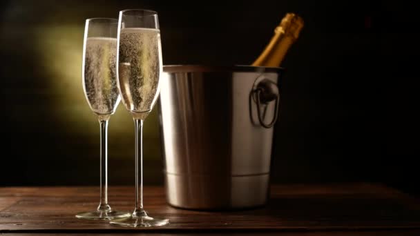Champagne. Two Flutes with bottle of champagne in an ice bucket at background. — Stock Video