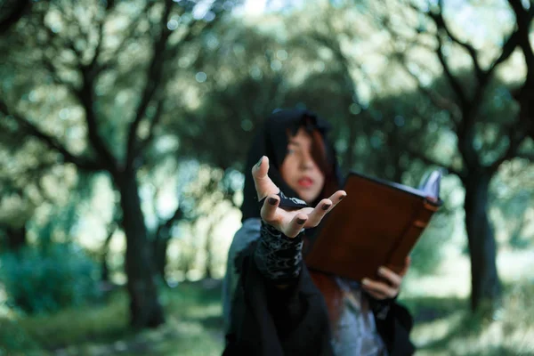 Kép a boszorkány a kinyújtott kéz és könyv — Stock Fotó