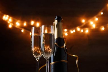 Yeni yıl fotoğraf iki şarap gözlük şarap, şişeler, mantar, yanan garland ile