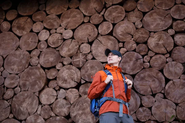 Mann mit Rucksack auf Wandhintergrund gefällter Bäume — Stockfoto