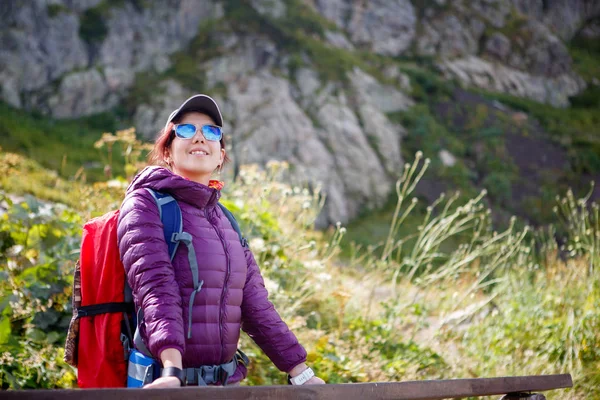 Foto da menina em óculos de sol com mochila no fundo das montanhas — Fotografia de Stock