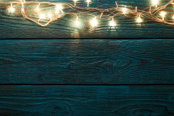 Foto de mesa de madera azul con guirnalda de Año Nuevo en llamas . —  Fotos de Stock