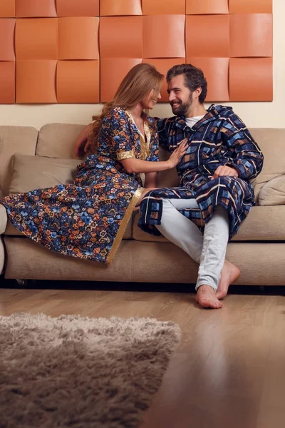 Image of long-haired blonde and men in homemade clothes hugging on sofa — Stock Photo, Image