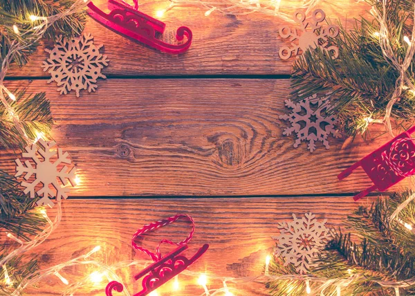 Foto en la parte superior de la superficie de madera con guirnalda ardiente, ramas de abeto, juguetes de Navidad , —  Fotos de Stock