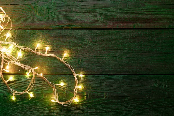 Picture of green wooden table with burning garland on side — Stock Photo, Image