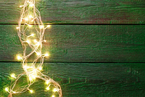 Image of green wooden table with burning garland on side — Stock Photo, Image