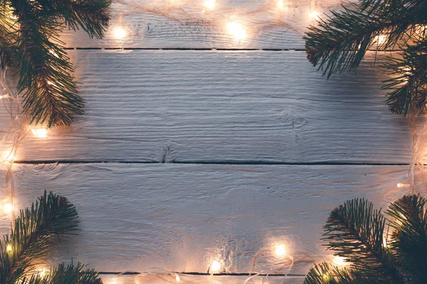 Photo of Christmas wooden gray surface with burning garland, branches of spruce. — Stock Photo, Image