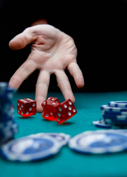 Foto de hombre tirando dados rojos en la mesa con fichas en el casino — Foto de Stock