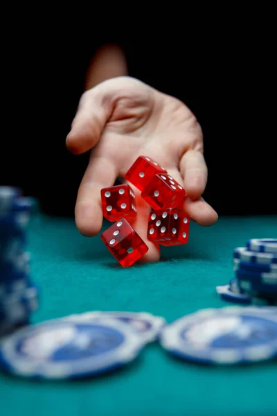 Imagen del hombre tirando dados rojos en la mesa con fichas en el casino — Foto de Stock