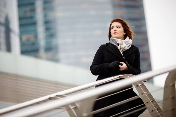 Фото женщины в черном пальто и шарфе на размытом фоне — стоковое фото